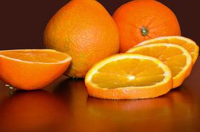 cut oranges are reflected on a wooden surface