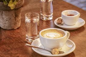 cups of coffee with glasses of water on a table in a cafe