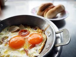 Delicious fried eggs with sausages in a pan