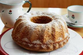 Beautiful cake with white sugar, near the colorful jug and cup