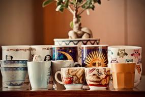 colorful Coffee Cups and mugs on shelf and tree in a pot