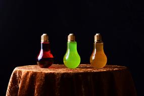 light bulbs as a bottles with colorful energy drinks at dark background