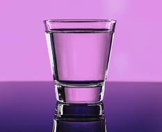 Clear liquid in glass at purple background