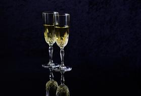 Two beautiful glasses with white wine at dark background