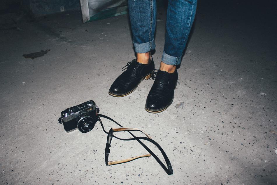 male feet, photo camera and eyeglasses on asphalt