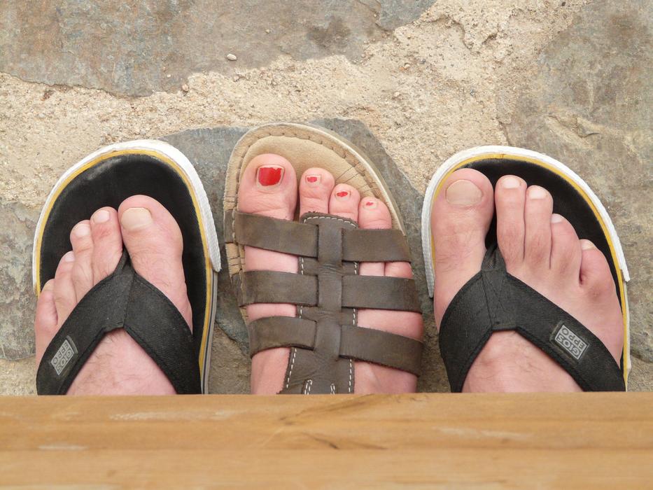female foot between male feet on sand