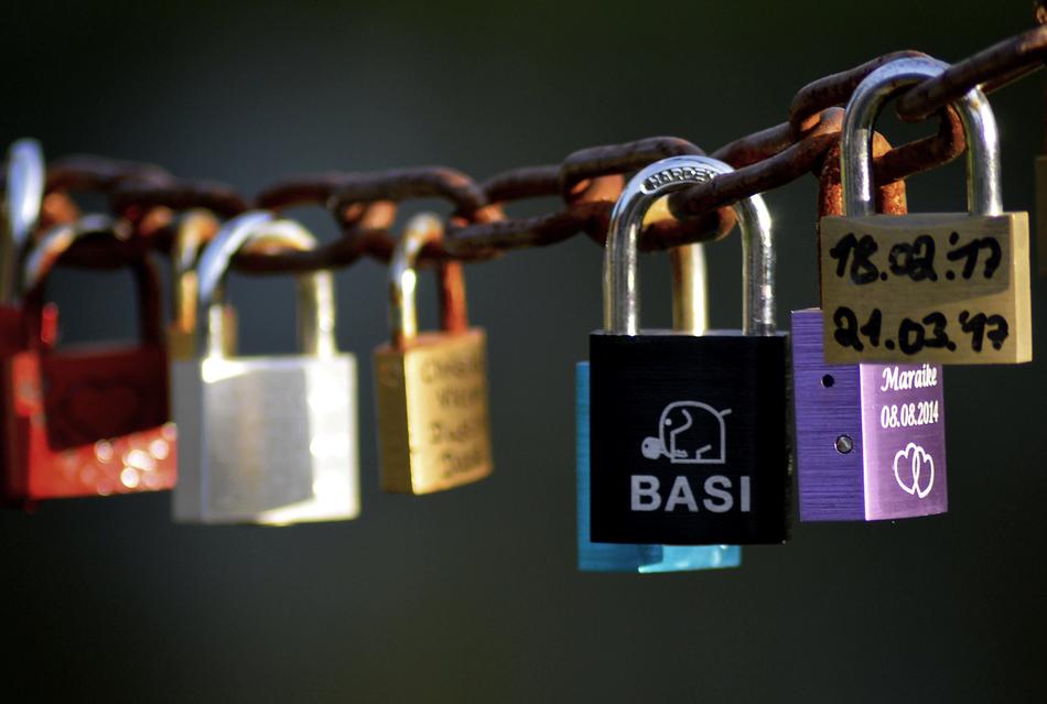 iron locks on a rusty chain with writing on them.