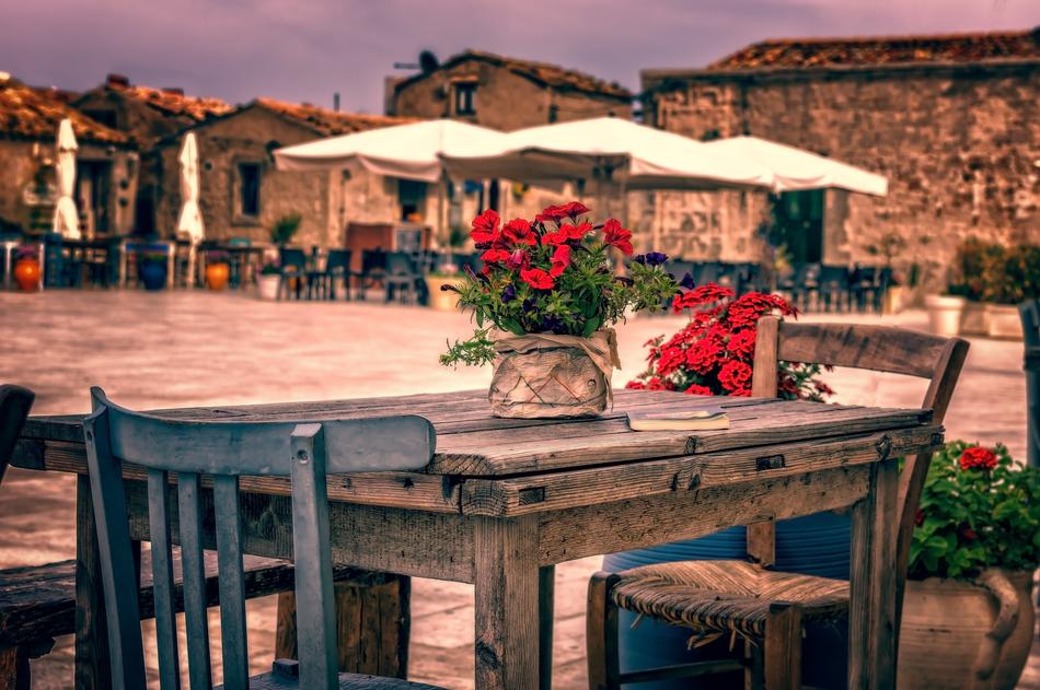 Beautiful wooden table and chairs with red flowers, on the terrace