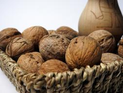 Beautiful, brown nuts in the wicket basket, near the pot, in autumn