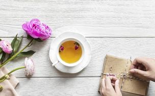 a bouquet of peonies, a cup with green tea and an envelope