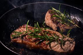 steak with rosemary on the pan