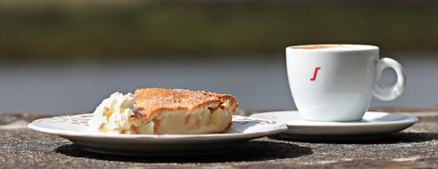 Beautiful and colorful apple pie on the plate, near the shiny cup of coffee, on the saucer