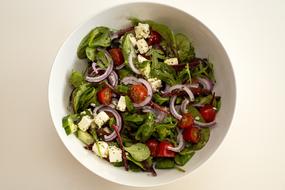 Colorful and beautiful salad with vegetables and feta cheese in white bowl