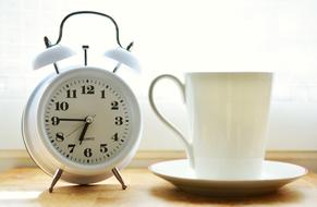 alarm clock and white cup