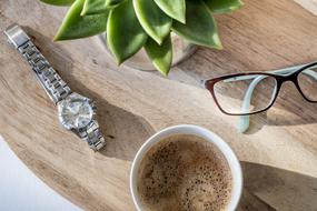 cup of coffee, glasses and a clock on the table