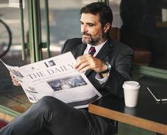 businessman drinking coffee and reading a newspaper on the street