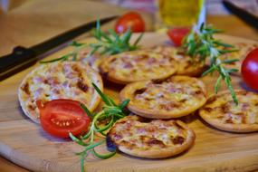 mini pizzas with rosemary and tomatoes on the wooden board