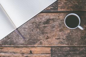 open notebook and cup of coffee on a wooden table