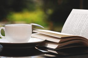 white cup with spoon and reading book close up