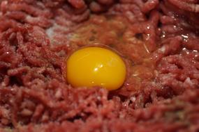 Close-up of the raw egg, on the raw, minced meat