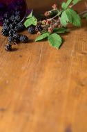 Beautiful and colorful berries with green leaves, on the wooden surface