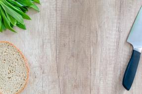 a piece of bread, greens and a knife on the table