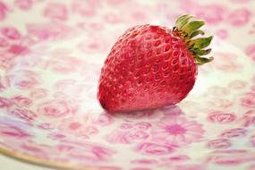 red strawberries with green leaves on a plate