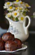 Chocolates on plate and daisies in jug