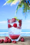 refreshing drink with raspberries on the beach