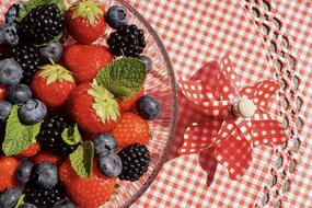 mix of fresh berries in a bowl on a checkered tablecloth