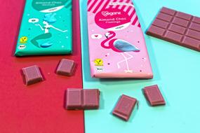 Beautiful chocolate bars and pieces in the colorful and beautiful packages, on the red and turquoise surface