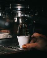 cup in female hand at Coffee Machine