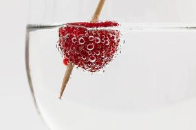 red raspberries with a toothpick in a glass of mineral water