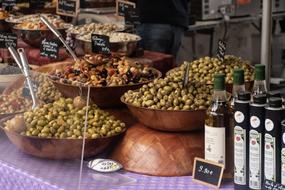 variety of olives and olive oil on the counter in the market