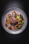 steak with tomatoes and arugula in a restaurant