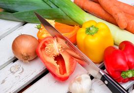 Knife on the colorful vegetables on wooden surface