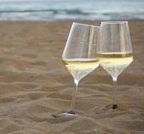 two glasses of champagne on warm sand at the beach