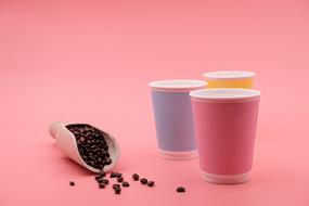 coffee beans in a wooden scoop and disposable glasses