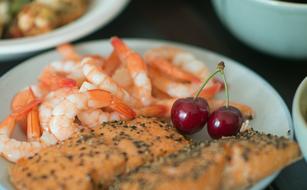 salmon in pepper, shrimp and cherry on a plate