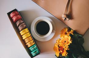 Coffee in Cup on Saucer, macaroons and flowers on table