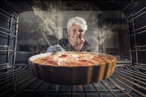 Apple pie Baking, mature woman at oven with pan