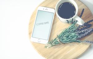 smartphone, cup of coffee and a bouquet of lavender on a wooden board