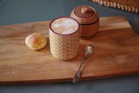 cup of cappuccino and homemade bun on a wooden board