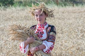 girl in national dress with a wheat crop in hands on a field in Burgas, Bulgaria