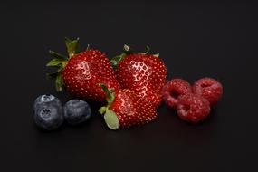blueberries, strawberries and raspberries on a black background
