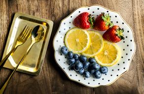 Plate with colorful fruits and gold cutlery