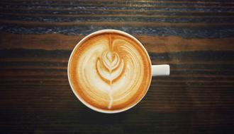 Cup of cappuccino with the drawing on the wooden surface