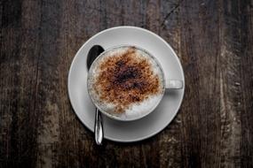cup of cappuccino with cinnamon on a wooden table