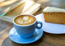 Cup with Coffee art and cake on wooden table