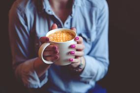 coffee with foam in female hands close-up on a blurred background